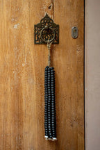 Pompon mural en perles de bois noires suspendu par cordon naturel