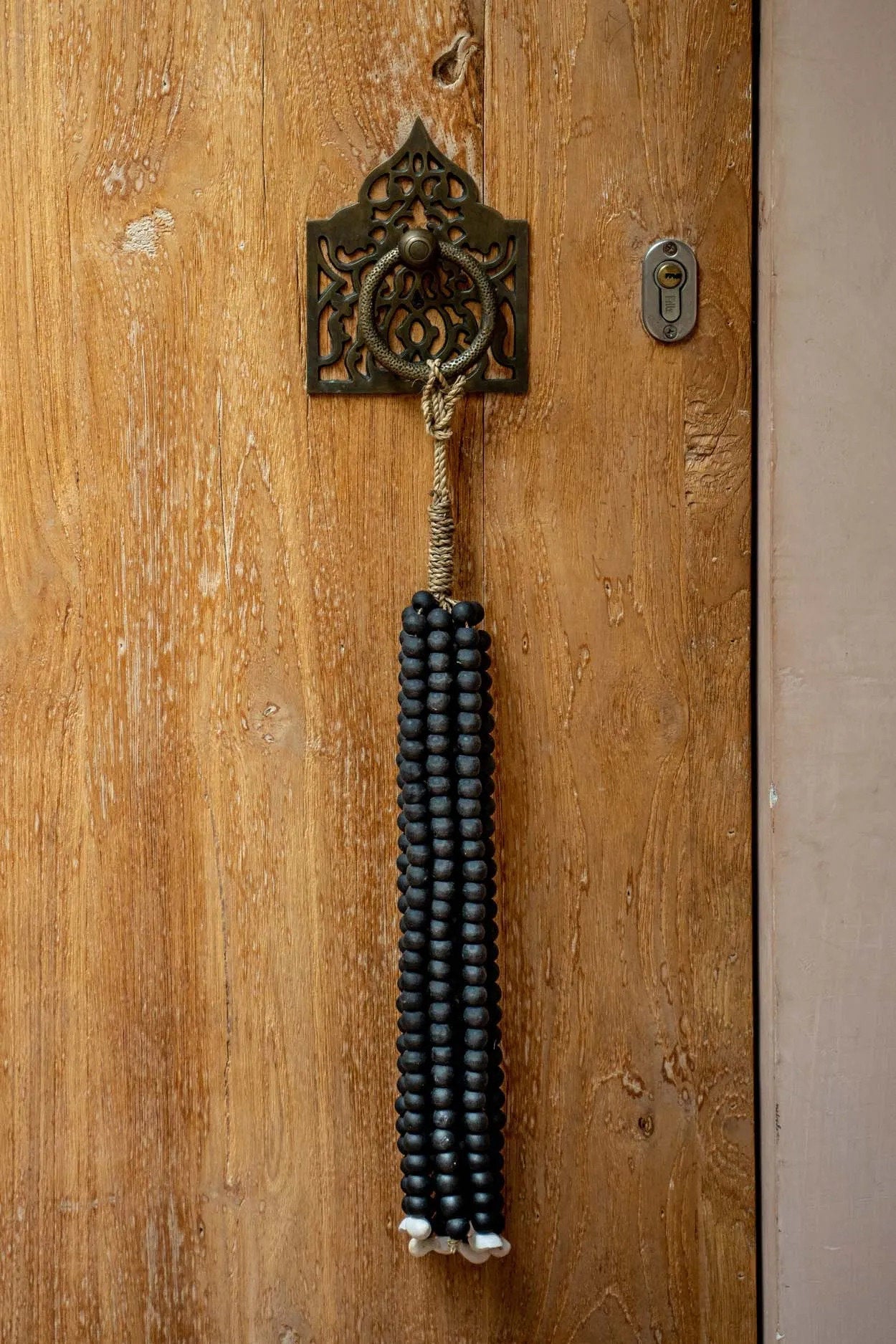 Pompon mural en perles de bois noires suspendu par cordon naturel
