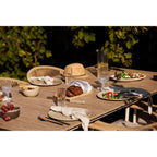 Table en bois d’extérieur avec chaises en rotin tressé et chapeau de paille