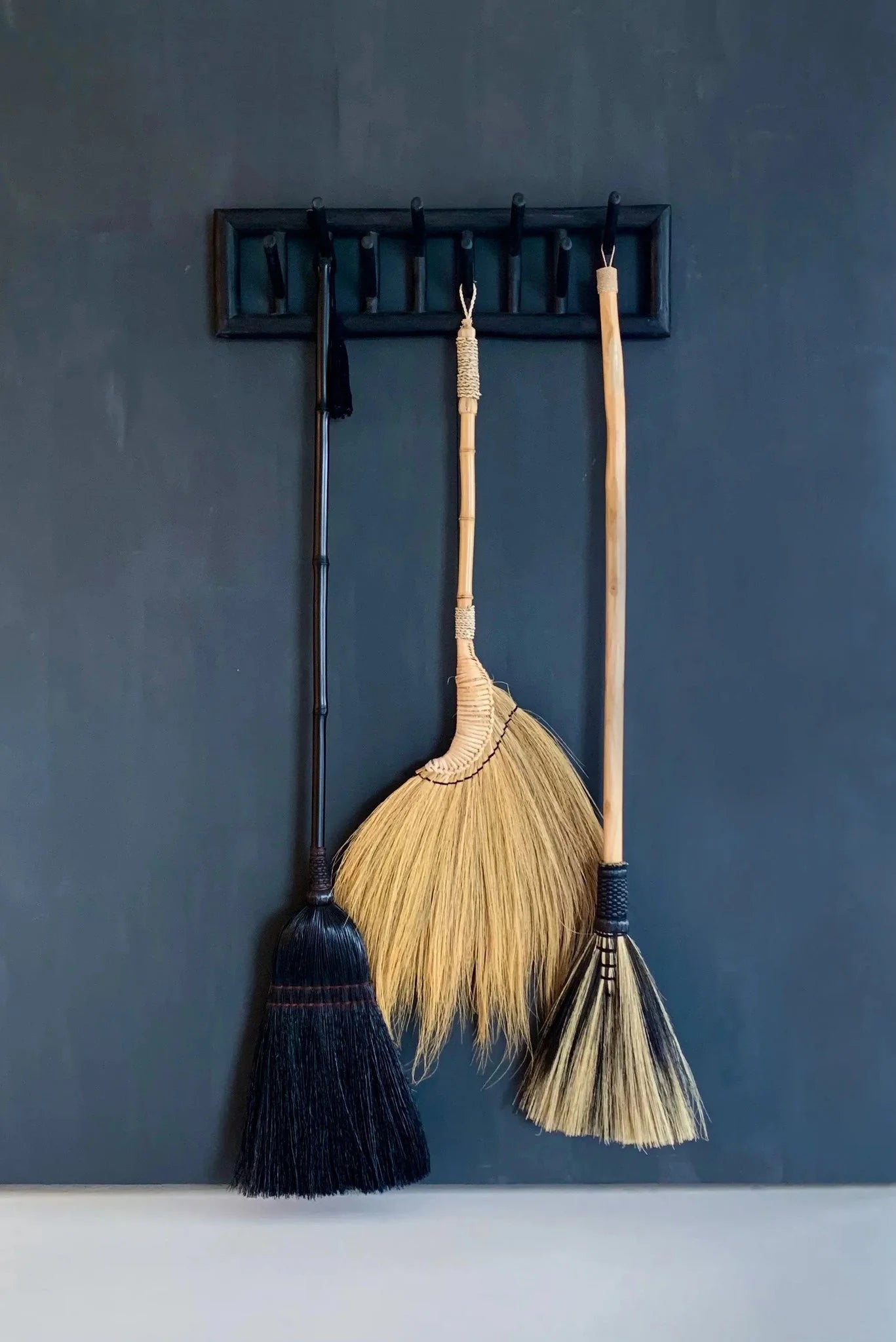 Trois styles de balais en fibres naturelles beige et noir avec manche en bois courbé
