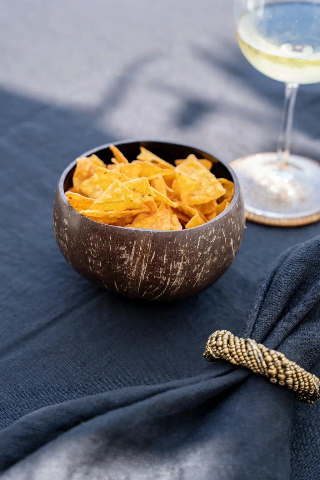 Bol en noix de coco naturelle brun foncé en forme ronde rempli de chips de tortilla