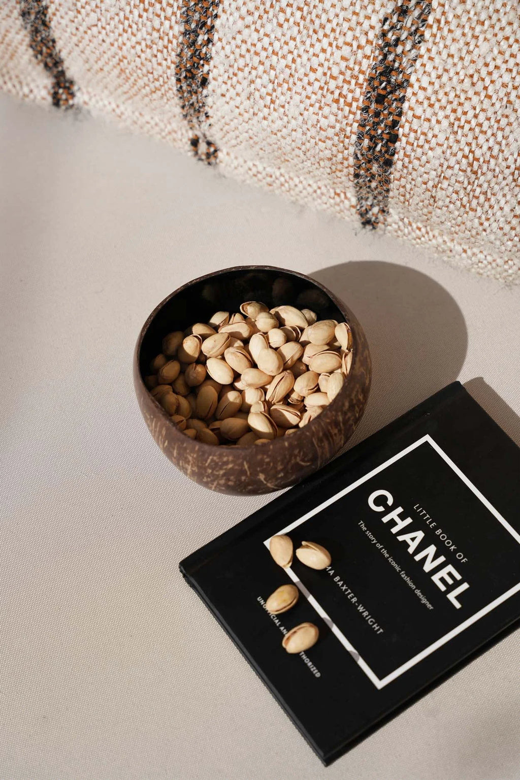 Bol en noix de coco naturelle brun foncé forme ronde rempli de pistachios