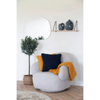 Fauteuil gris texturé avec coussin et couverture ocre recyclé