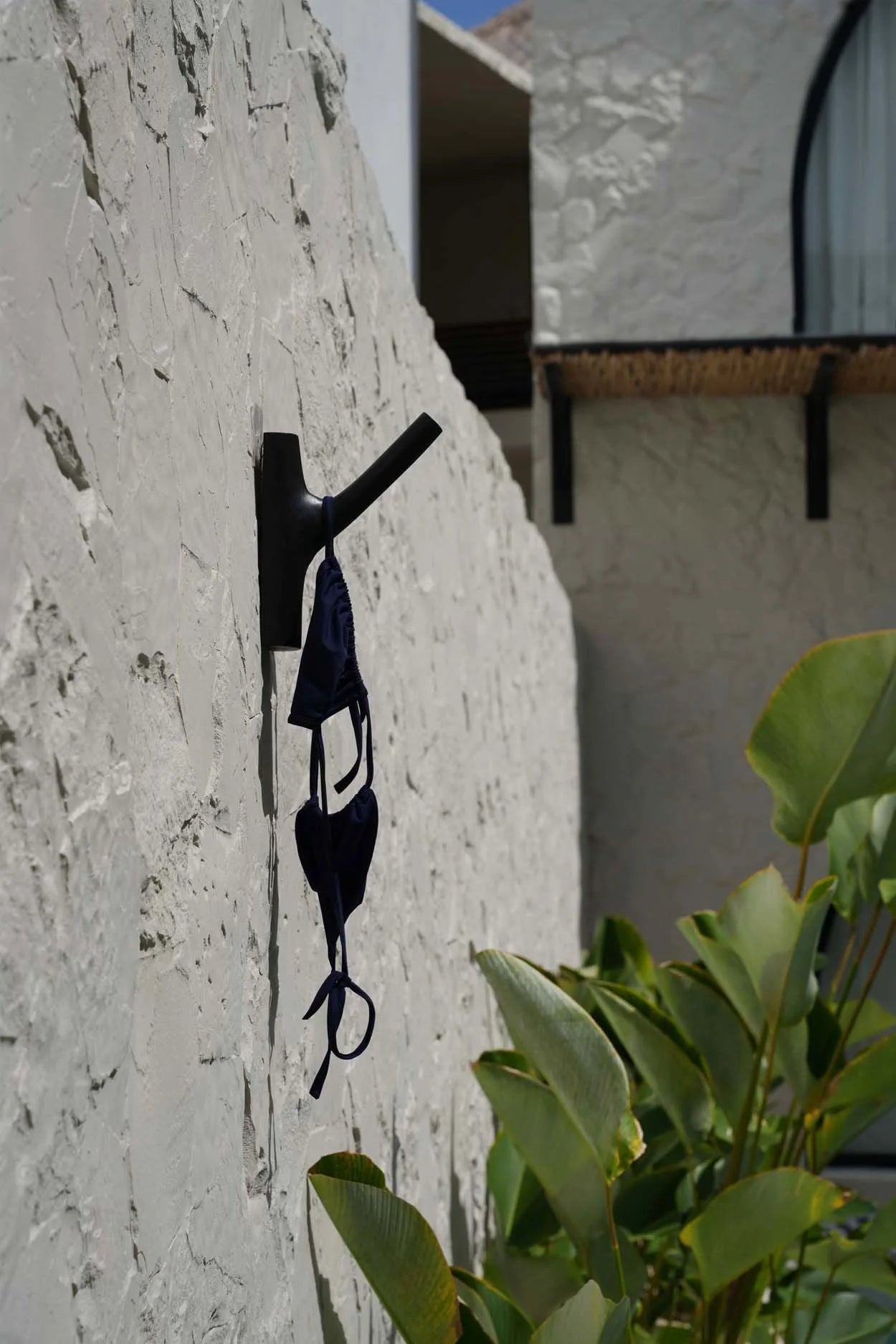 Bikini noir en crochet suspendu sur un crochet mural dans la pièce design Teck Noir