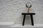 Tabouret minimaliste noir avec collier décoratif en éléments noirs et franges naturelles