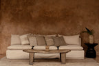 Canapé beige capitonné avec coussins en lin texturé écru et table basse pierre