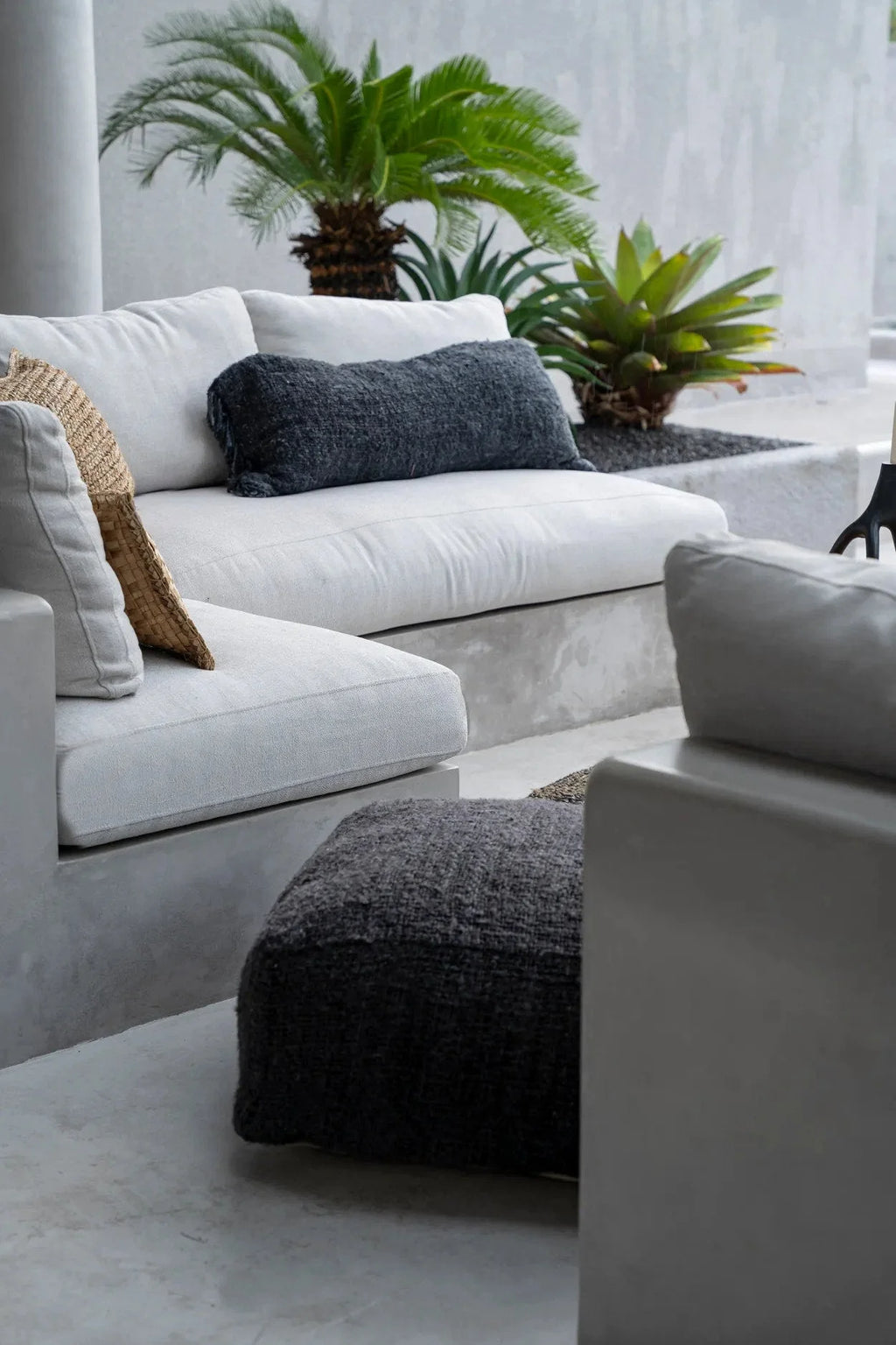 Canapé sectionnel blanc avec coussins gris et ottomane noire texturée, design moderne