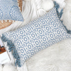 Housse de coussin bleu géométrique avec franges posée sur un canapé