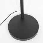 Base circulaire noire mate avec tige cylindrique, lampe en rotin tressé noir et beige sur arches métal noir H180 cm