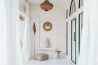 Miroir mural rond en raphia naturel et coquillages dans une pièce blanche minimaliste boho