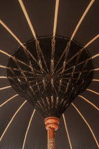 Intérieur de parapluie balinais rond en tissu noir avec supports en bois et décorations