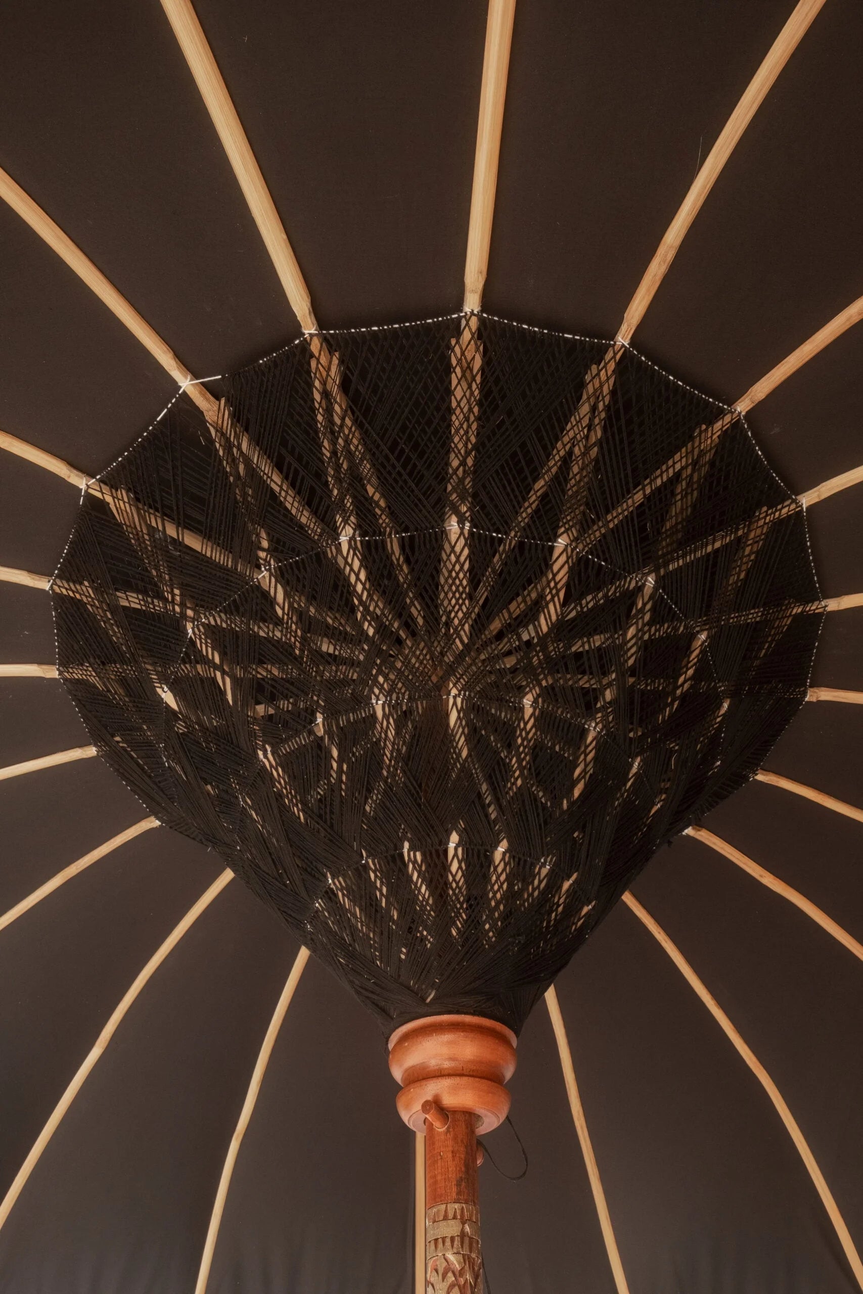 Intérieur de parapluie balinais rond en tissu noir avec supports en bois et décorations