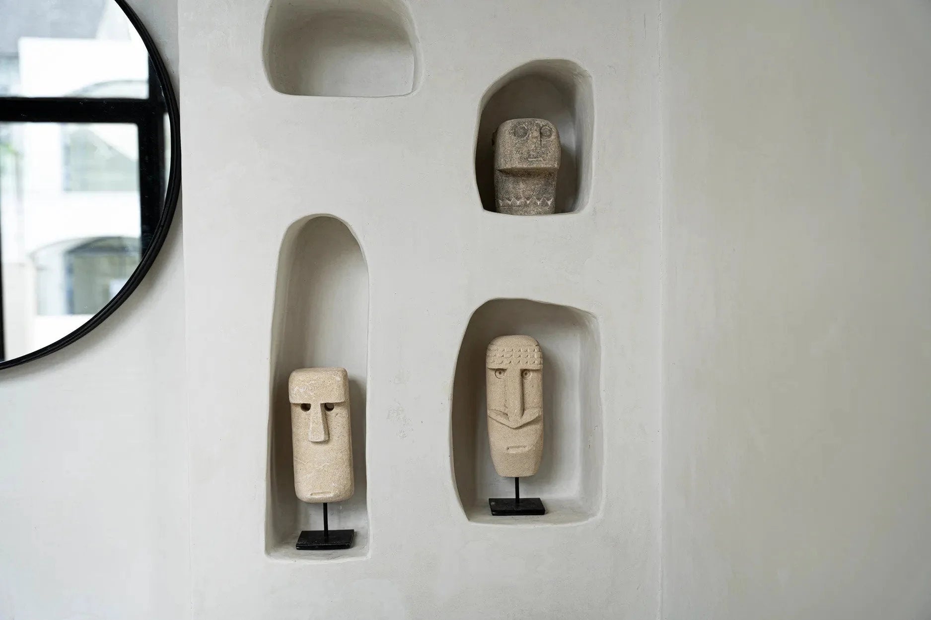 Mur avec niches intégrées affichant des sculptures décoratives Moai en grès beige sculpté à la main