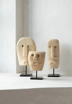Trois sculptures en bois sculpté avec des visages abstraits sur supports en métal noir