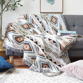 Plaid aztèque à franges posé sur un canapé avec des motifs ethniques colorés