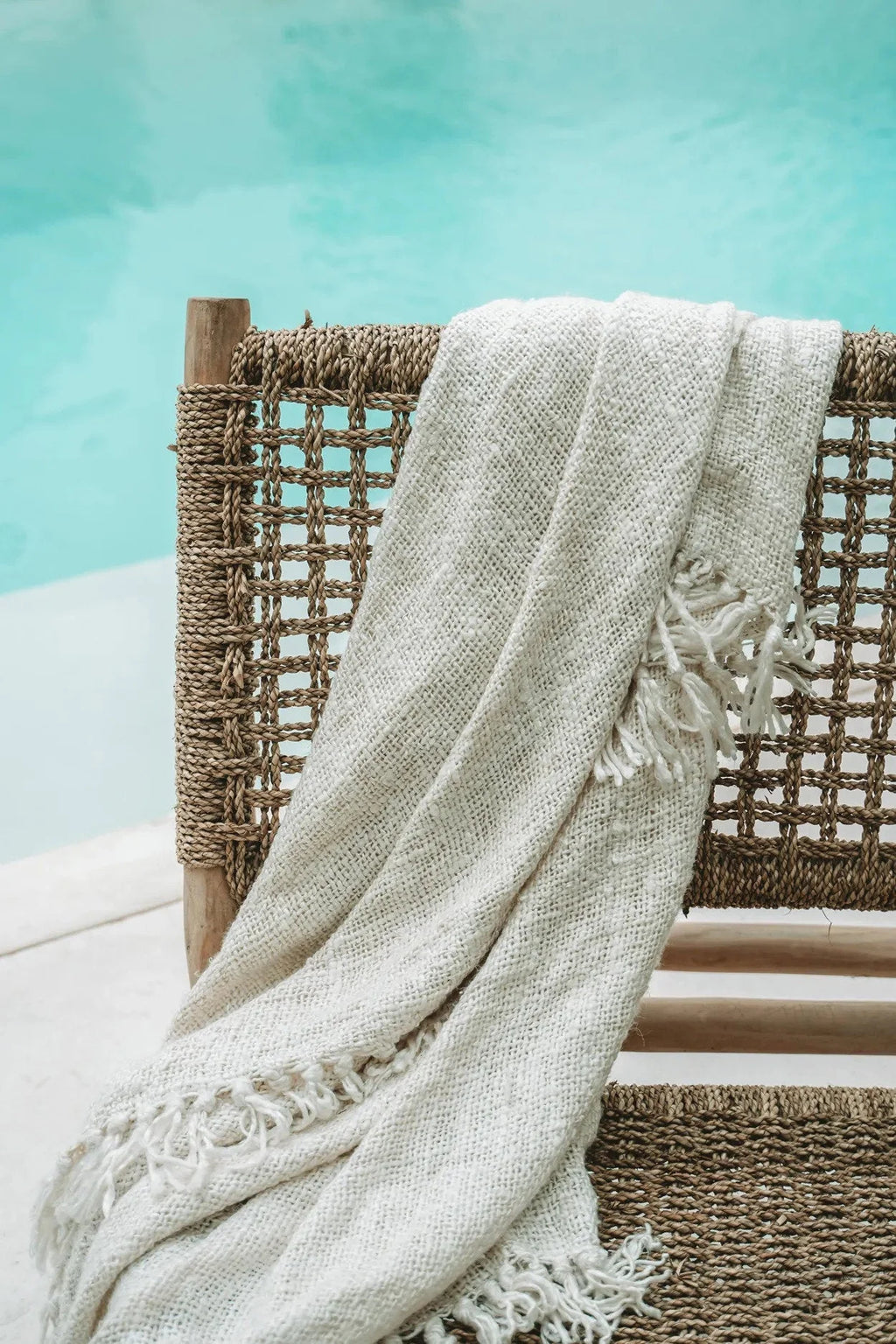 Plaid en coton gaufré crème avec franges décoratives sur une chaise en osier extérieure