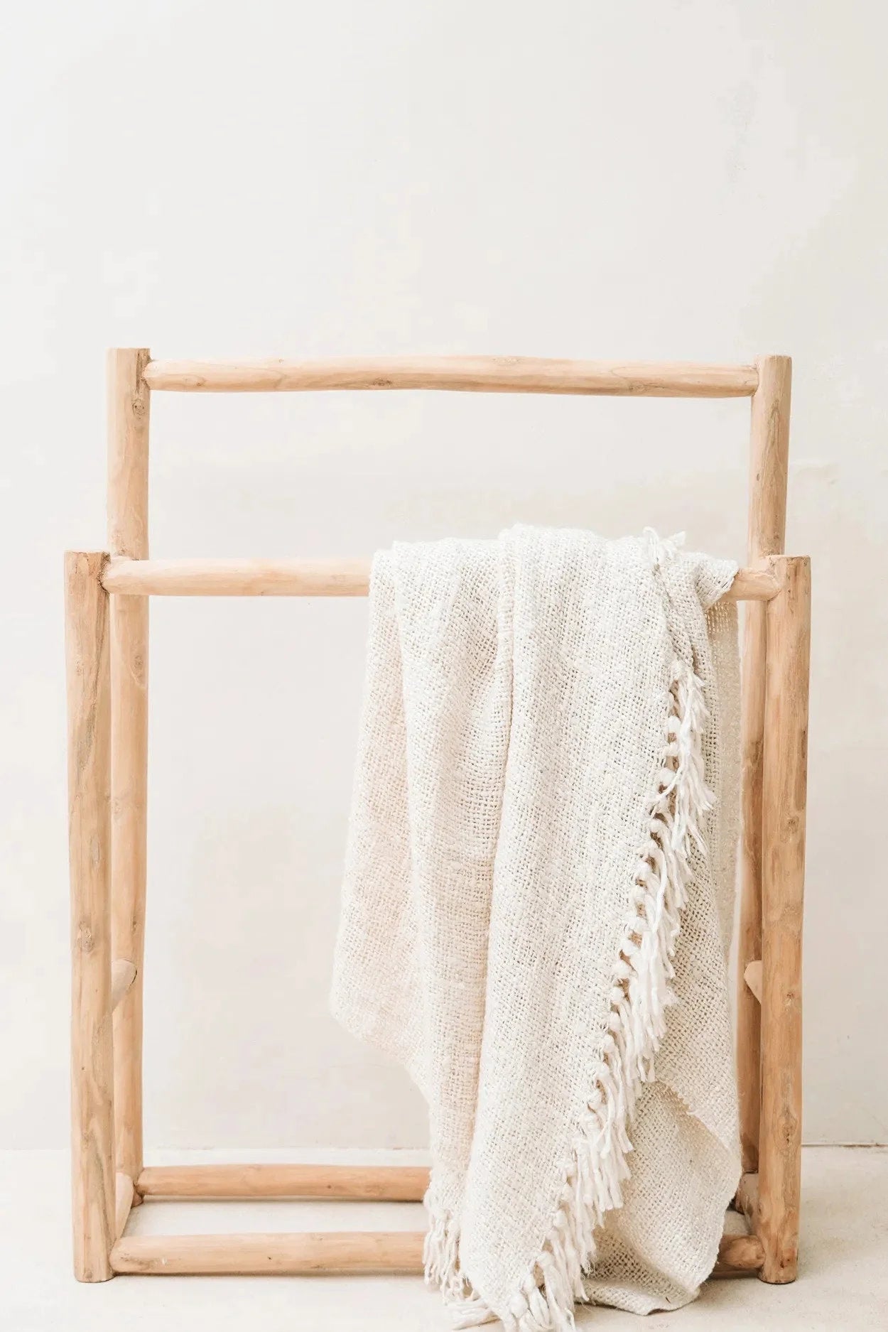 Towel rack en bois clair avec couverture en coton gaufré crème à franges décoratives