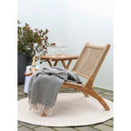 Chaise longue en bois clair avec dossier et assise en osier beige et plaid coton gris-beige frangé
