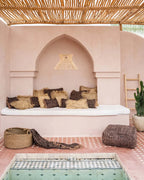Coin salon extérieur marocain avec banquette, coussins et petite piscine, plaid en coton noir cuivre