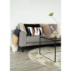 Canapé gris capitonné avec coussin rayé et plaid à franges gradient camel anthracite