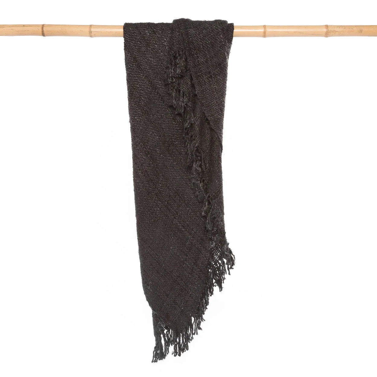 Plaid rectangulaire en coton tissé noir avec franges, drapé sur une barre en Bambou