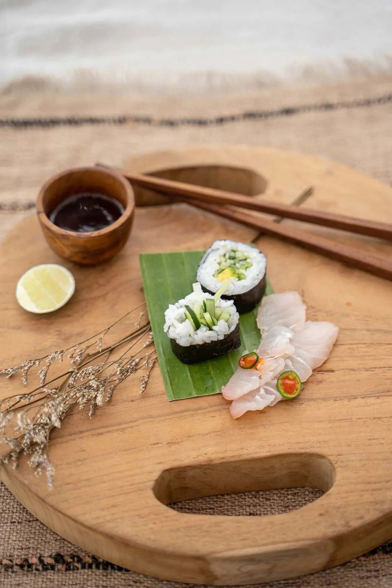 Sushis frais avec sauce et citron sur plateau rond en racine de teck Ø35 cm