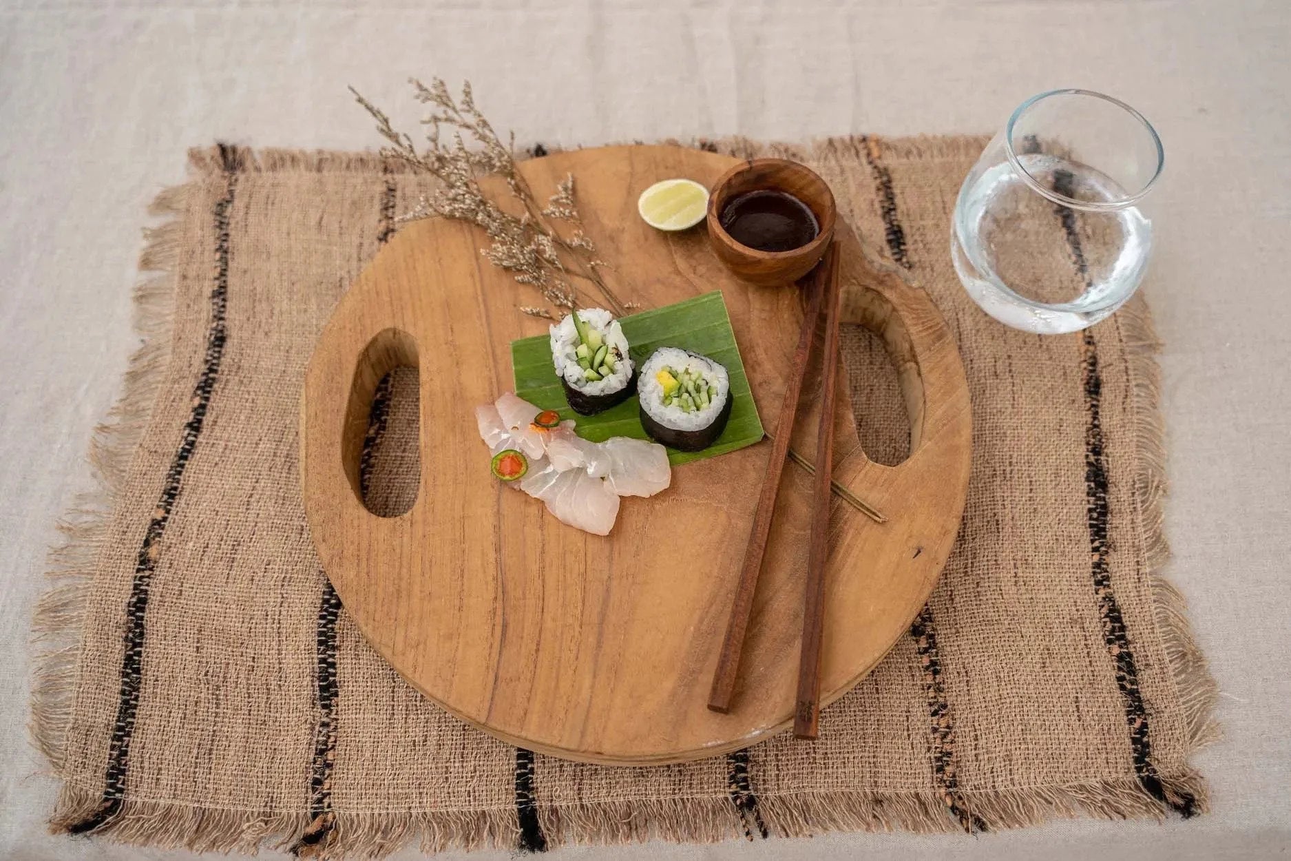 Sushi présenté sur un plateau rond en teck naturel avec poignées ajourées Ø30 cm