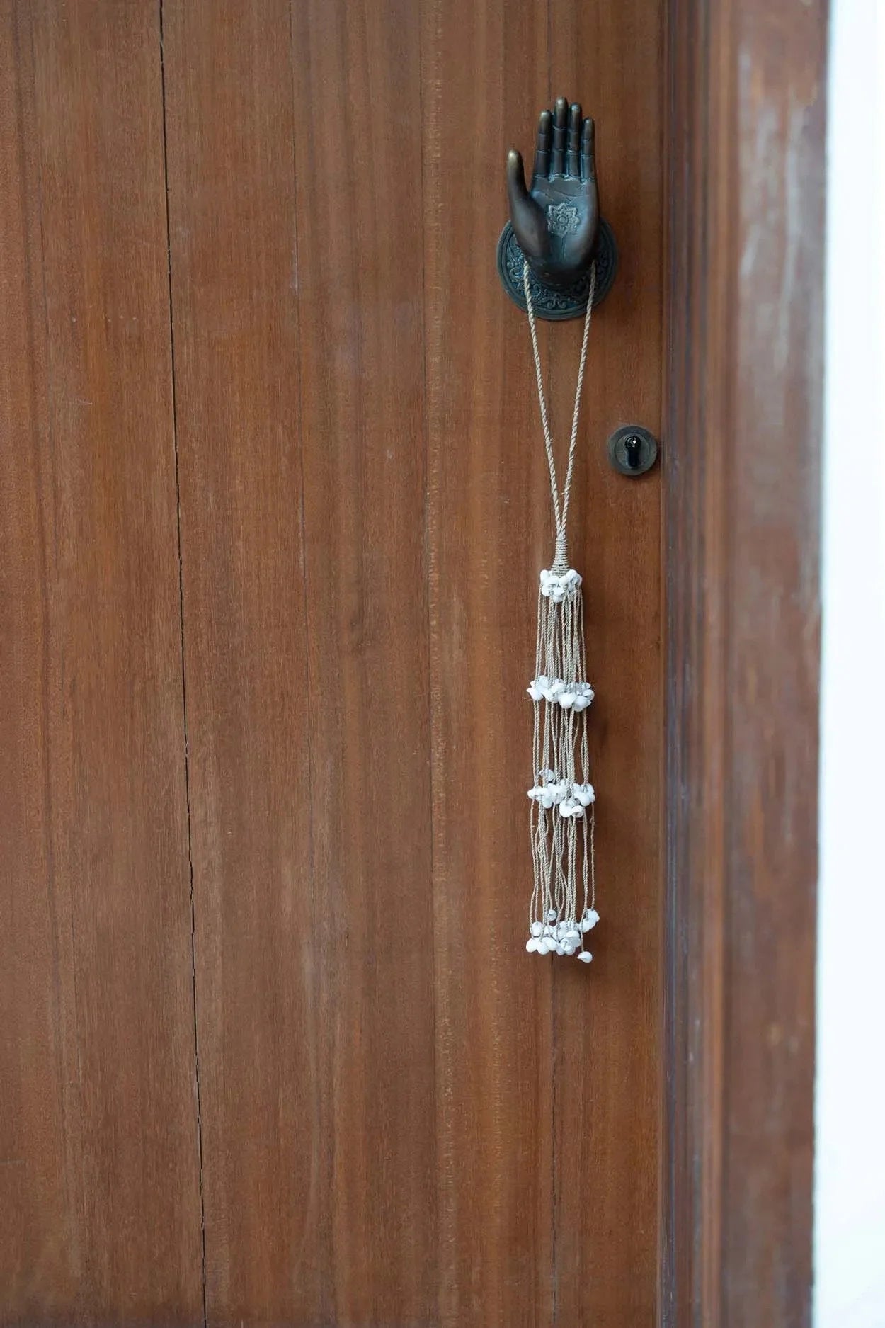 Pompon décoratif en coquillages blancs, cordes naturelles et heurtoir en bois en forme de main