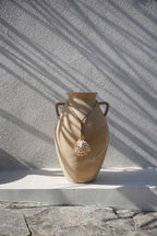 Vase en céramique beige avec deux anses et collier de pompons en coquillages naturels