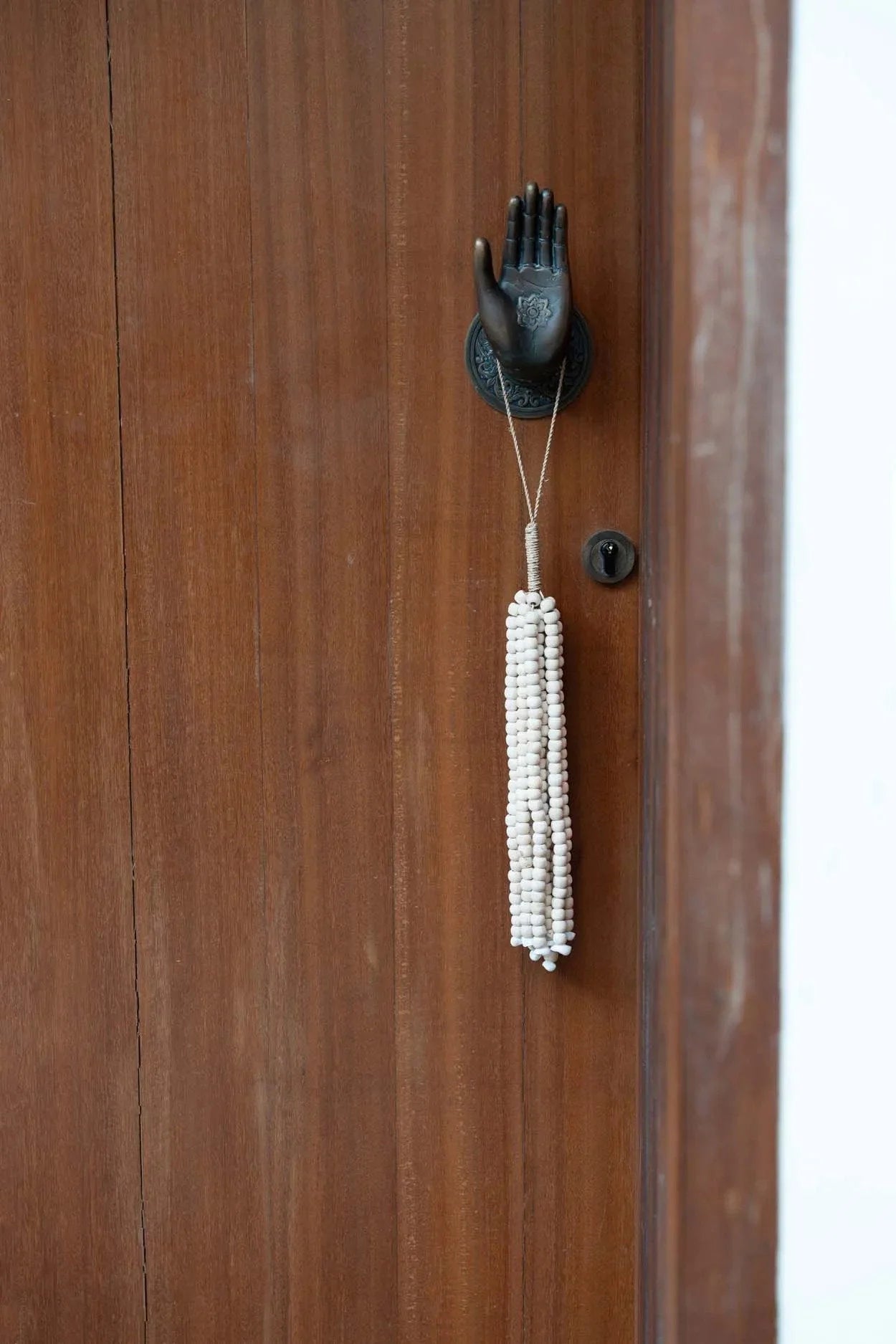 Poignée de porte en forme de main noire avec un pompon en perles de bois naturel