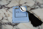 Porte-clés Prada coquillage cauri noir et blanc avec pompon en coton et cuillère blanche sur marbre
