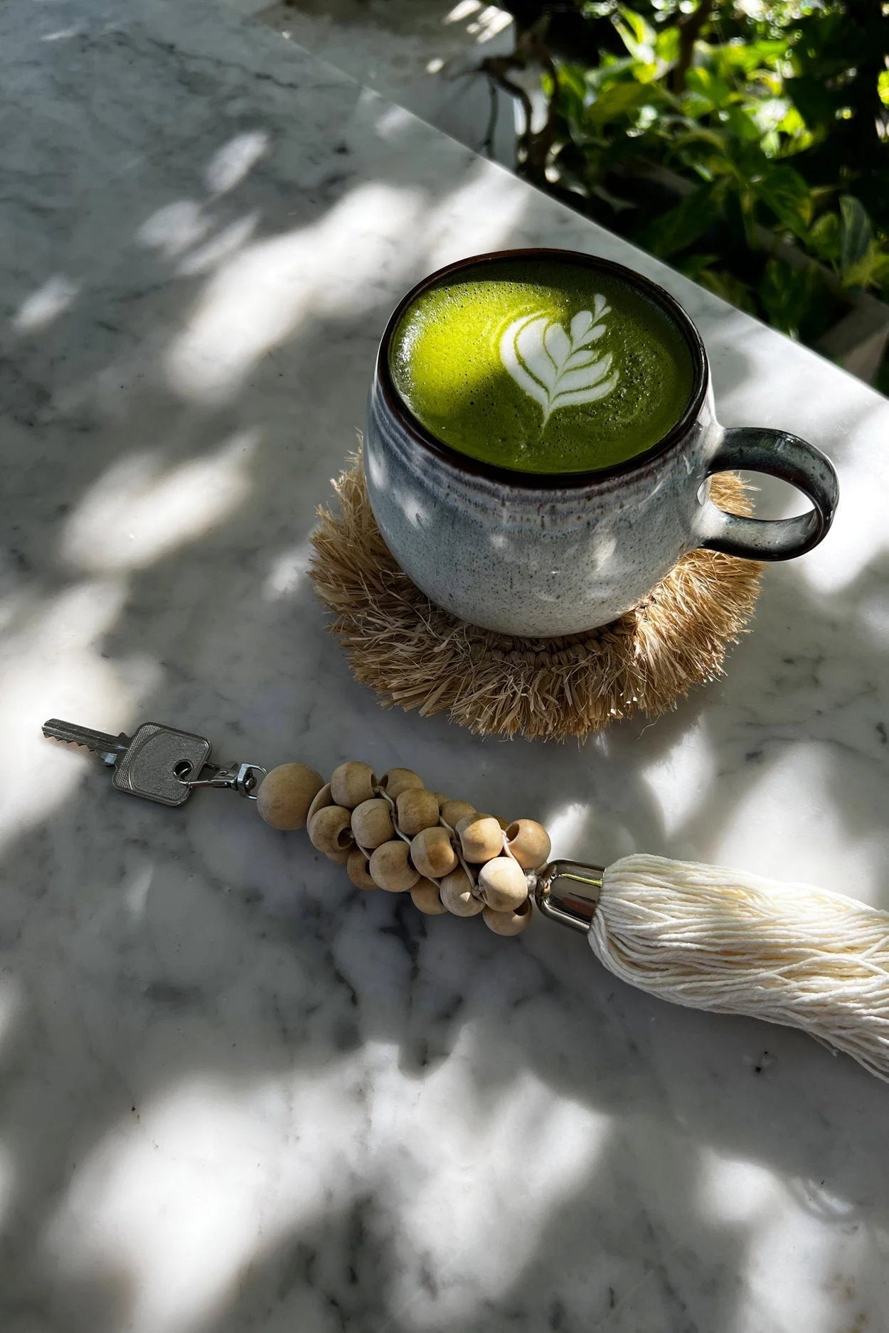 Latte matcha vert avec design feuille dans mug sur sous-verre paille