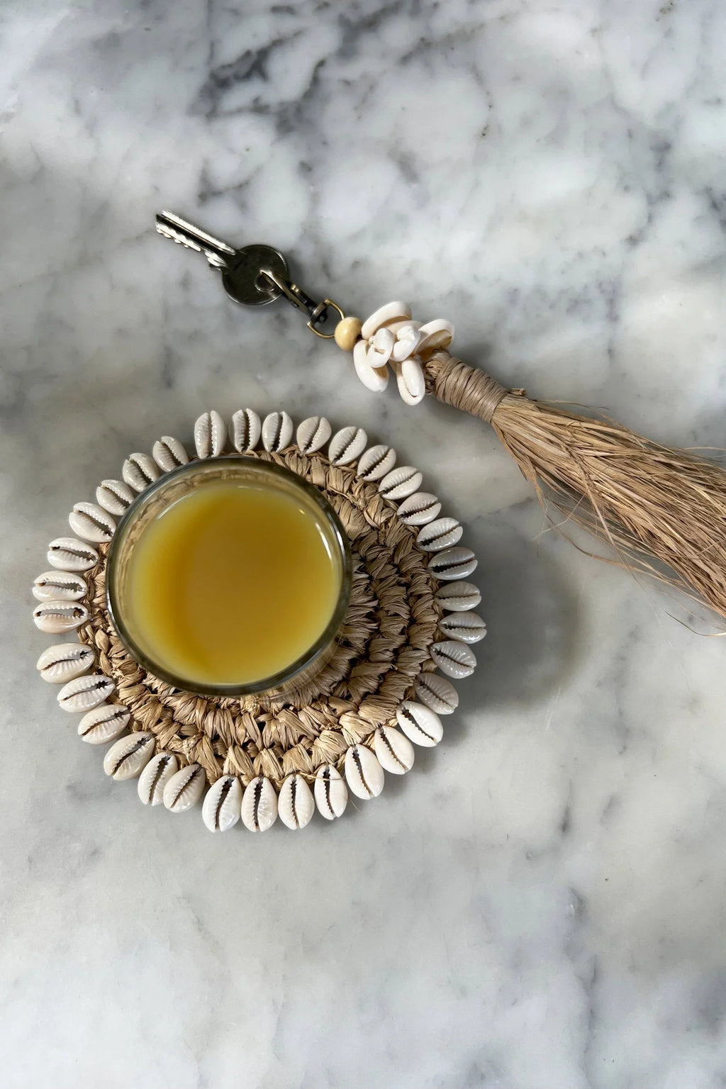 Porte-clés pompon en raphia avec coquillages blancs et liquide jaune