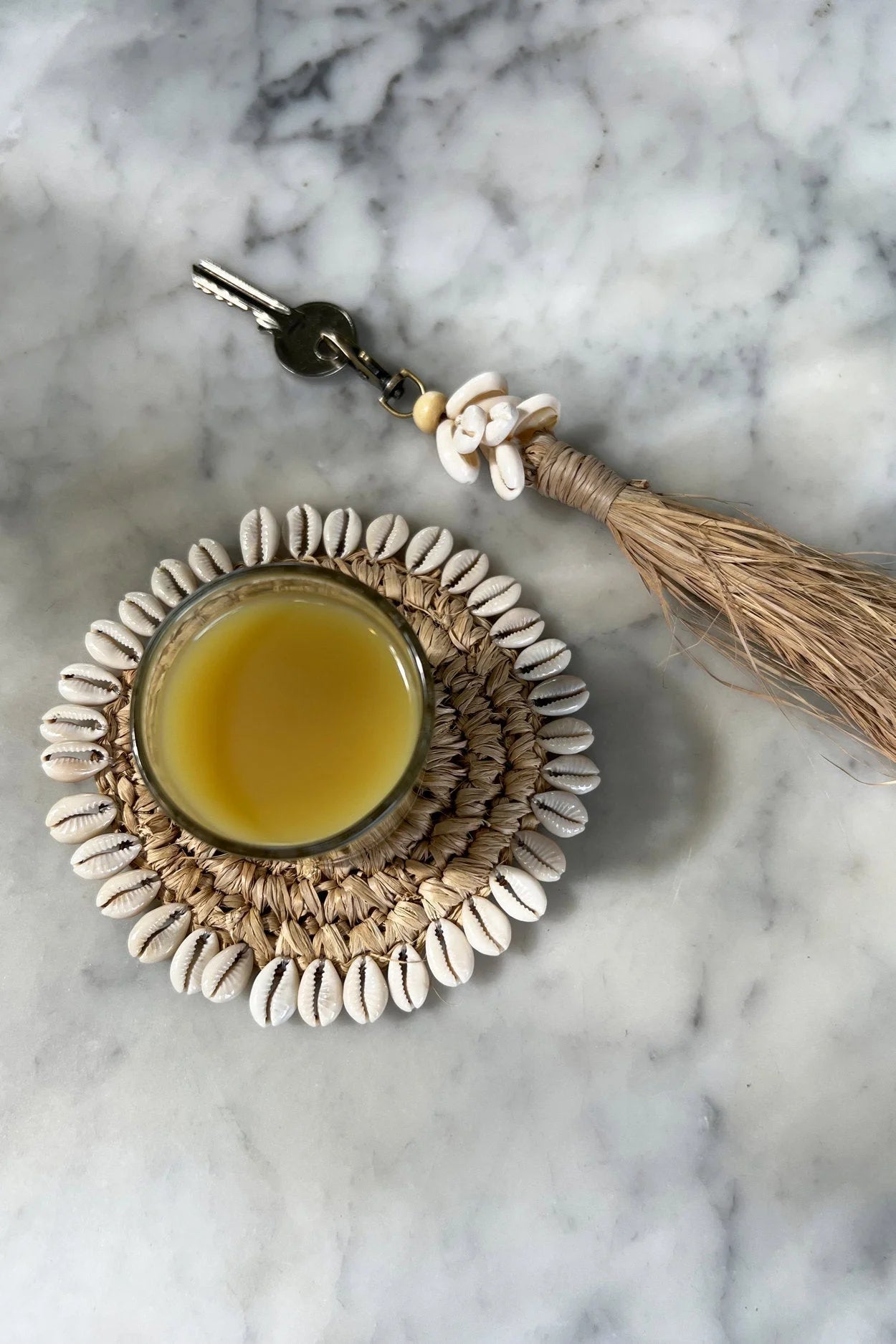 Porte-clés pompon en raphia avec coquillages blancs et liquide jaune