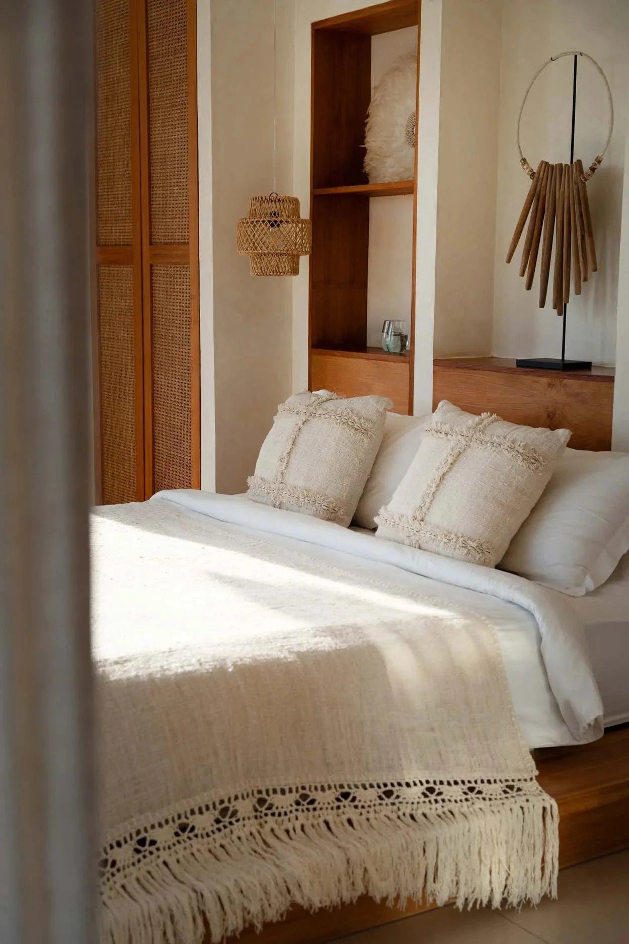 Lit avec linge blanc et coussins décoratifs à franges, idéal pour la décoration intérieure