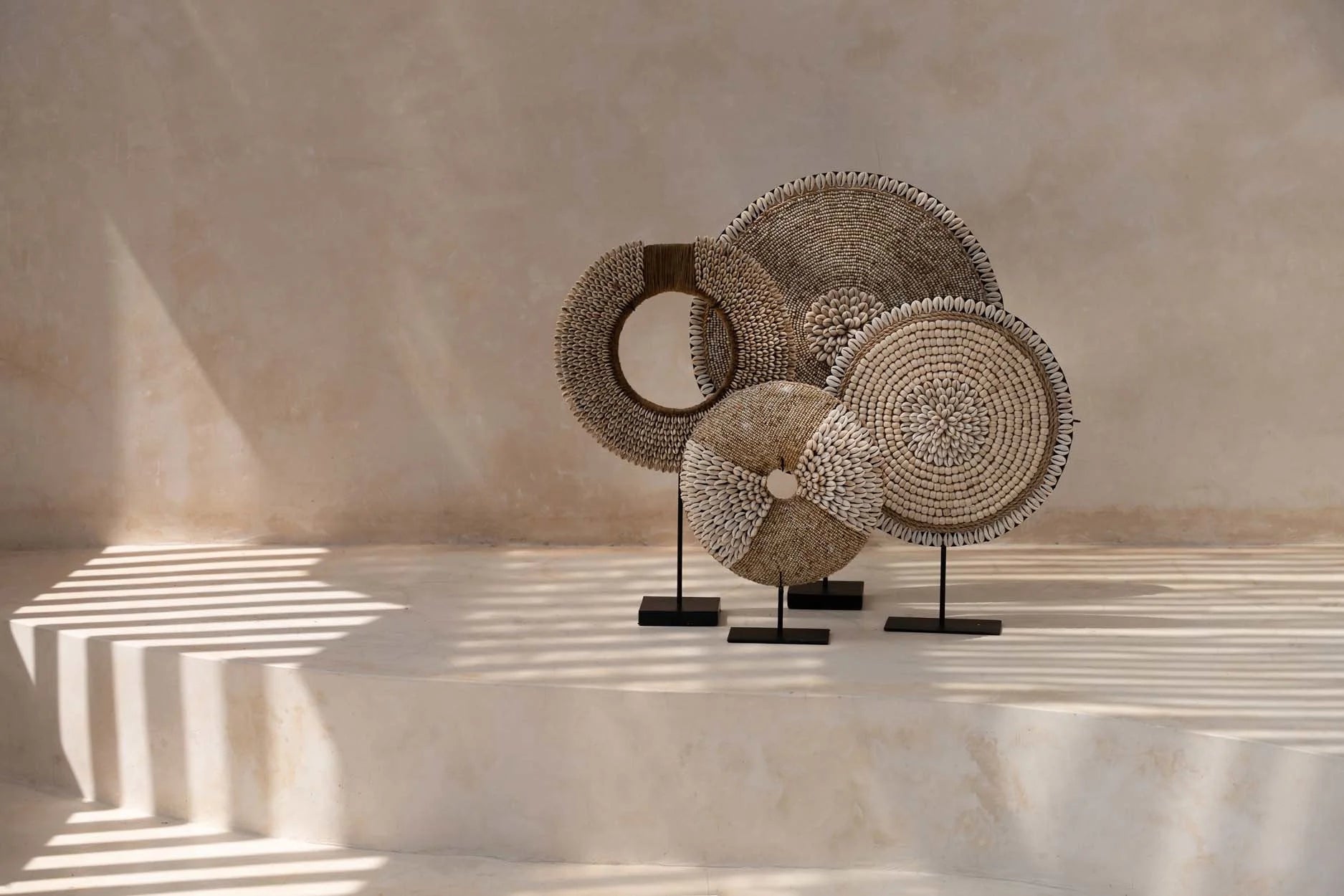 Objet décoratif rond en fibres naturelles et coquillages sur socle noir