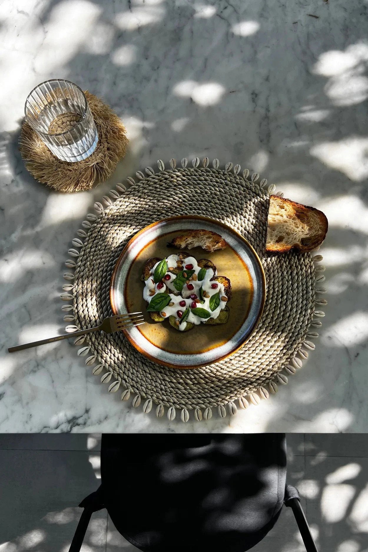 Assiette de toast à l avocat avec yaourt, graines de grenade et basilic, avec set de table rond en jonc de mer avec coquillages naturels
