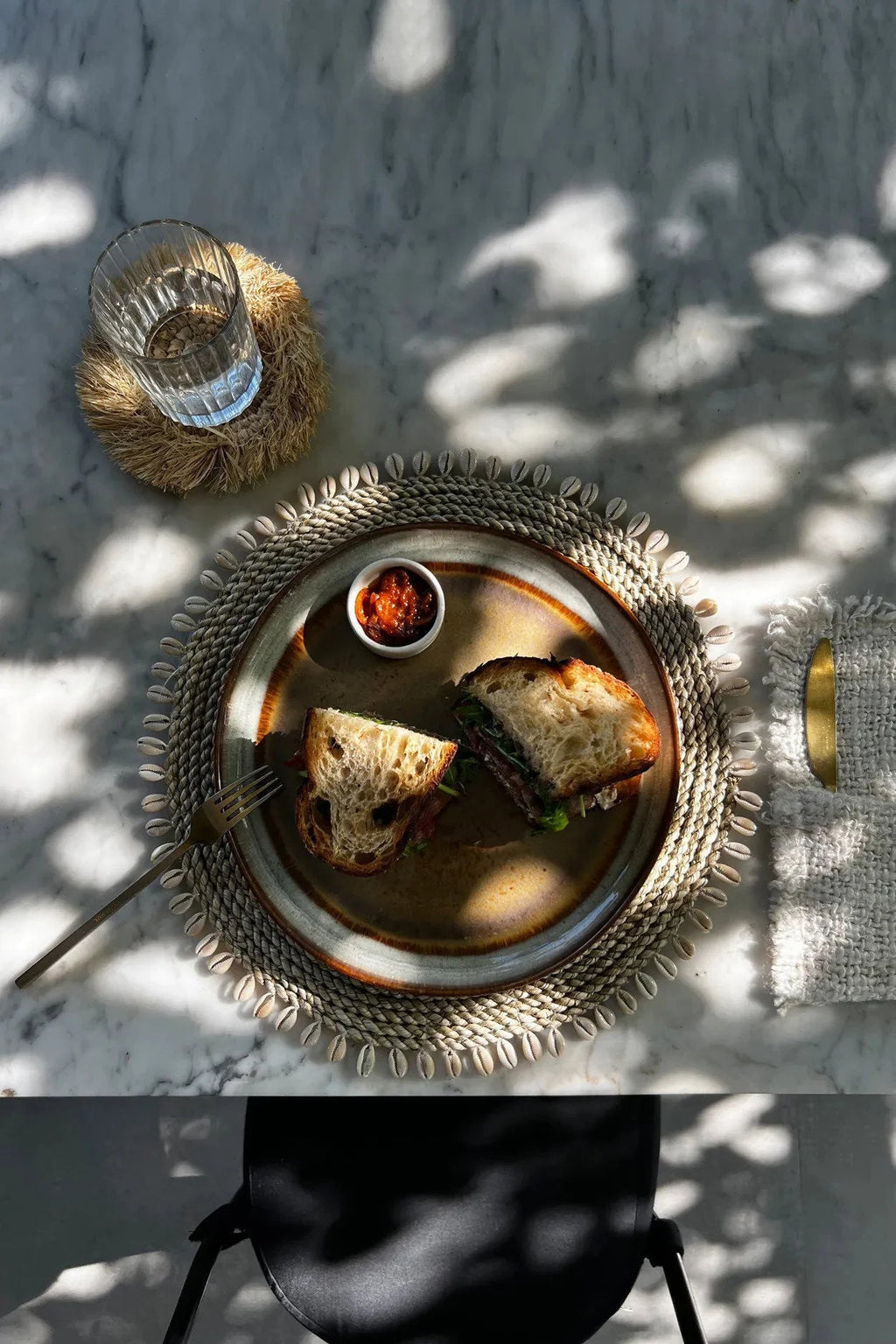Deux moitiés de sandwich sur une assiette en jonc de mer avec relish rouge naturelle