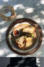 Sandwich coupé avec sauce, présenté sur un set de table rond en rotin tressé marron naturel