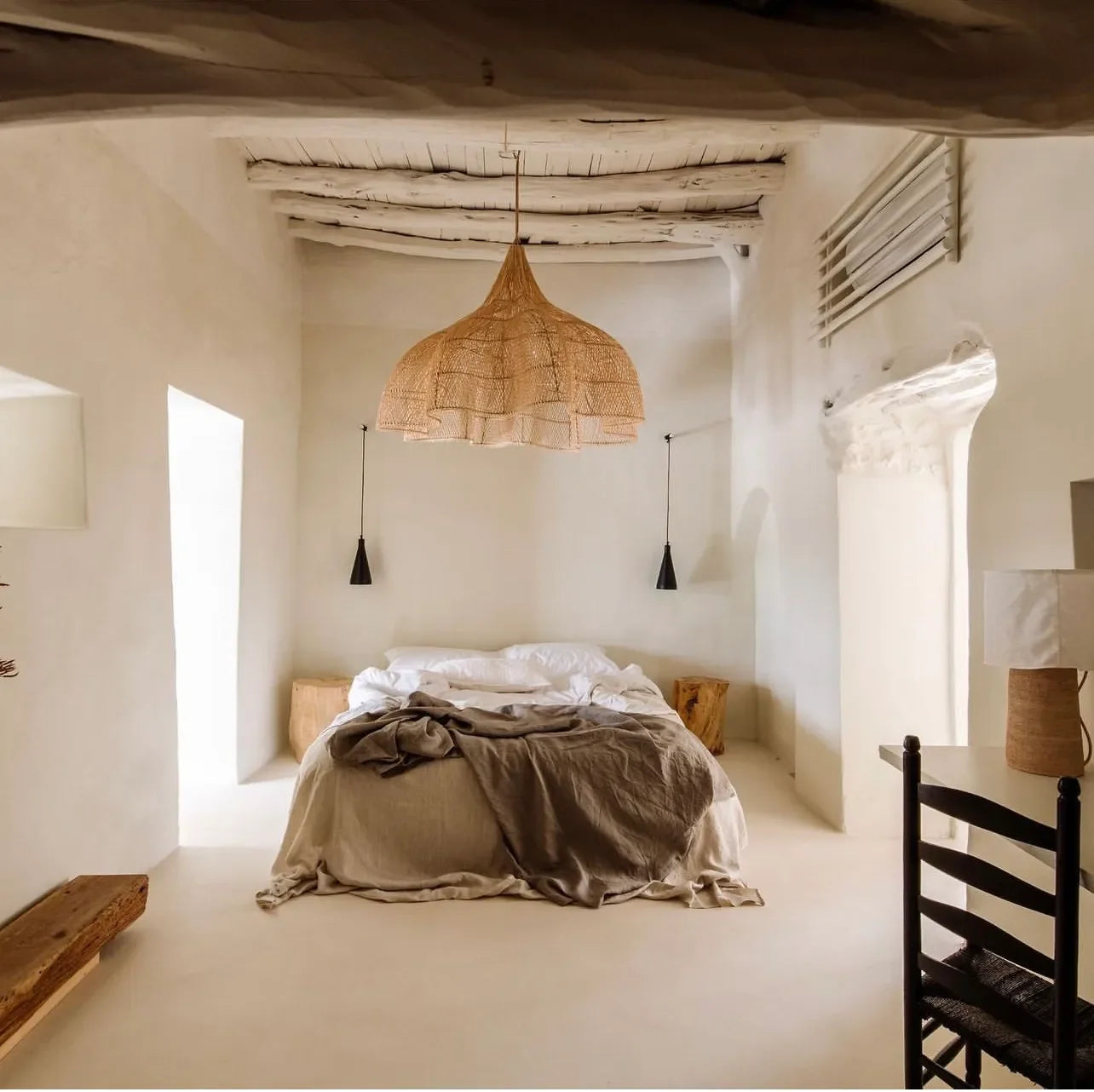 Suspension XXL en rotin naturel tressé dans une chambre lumineuse avec accents rustiques