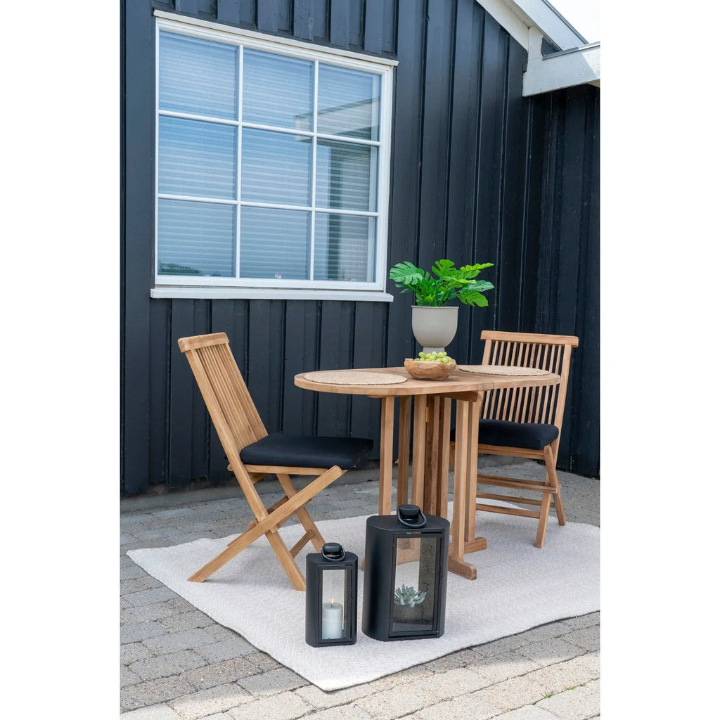 Table de balcon en teck naturel ovale avec chaises noires et lanternes