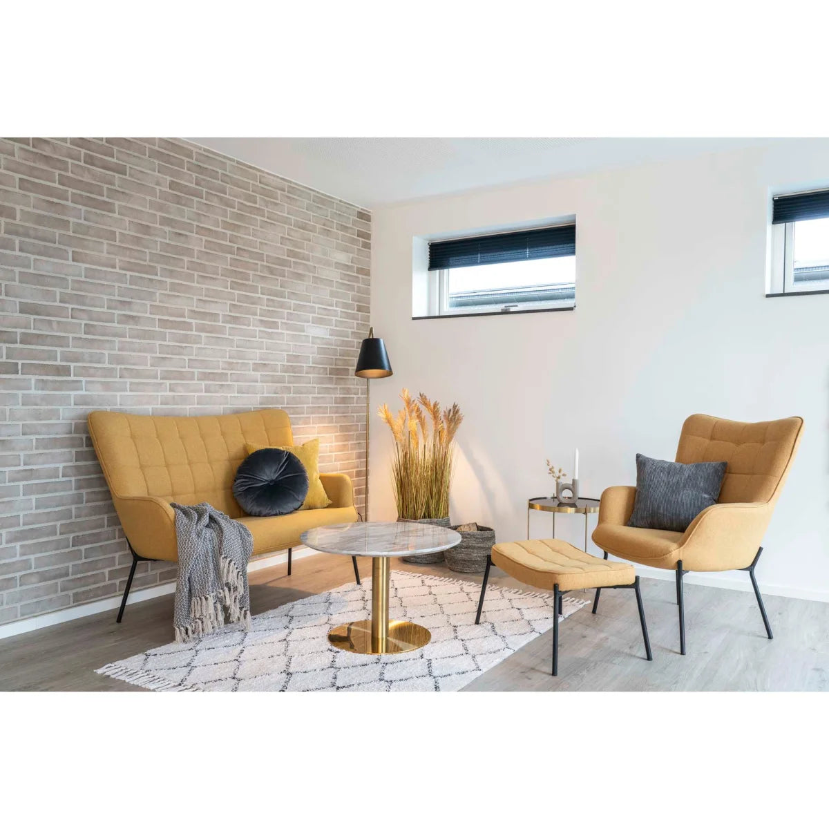 Canapé moutarde capitonné, pieds métal noir, plaid gris, avec table basse marbre blanc pied doré Ø70xH45 cm