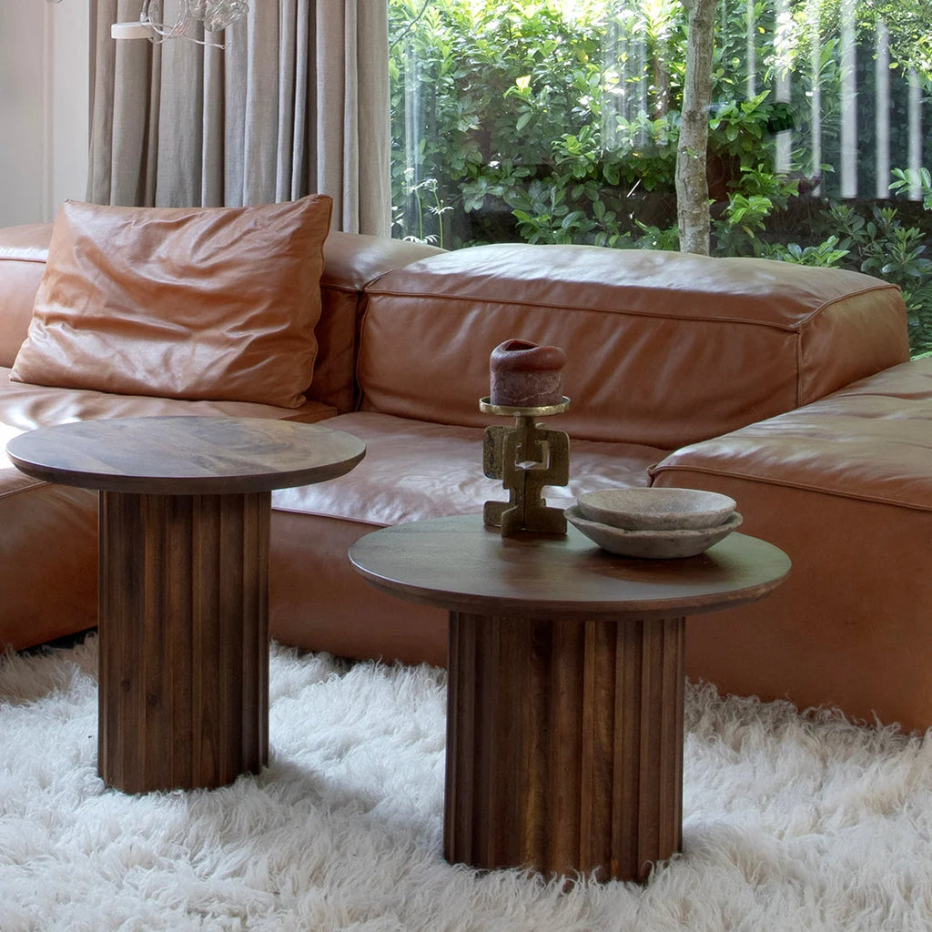 Deux tables d’appoint rondes en bois brun foncé cannelé sur tapis blanc