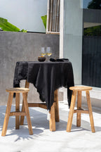 Nappe en lin noir aux bords effilochés sur tabourets en teck recyclé H66 cm