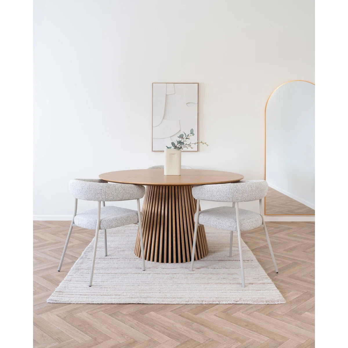 Table ronde en bois avec base cannelée et deux chaises tapissées, près d’un tapis rectangulaire fait main en laine ivoire à rayures 160x230 cm