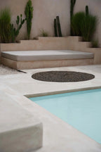 Espace détente extérieur avec banquette, fontaine rocheuse et piscine, Tapis rond en jonc de mer noir 150 cm