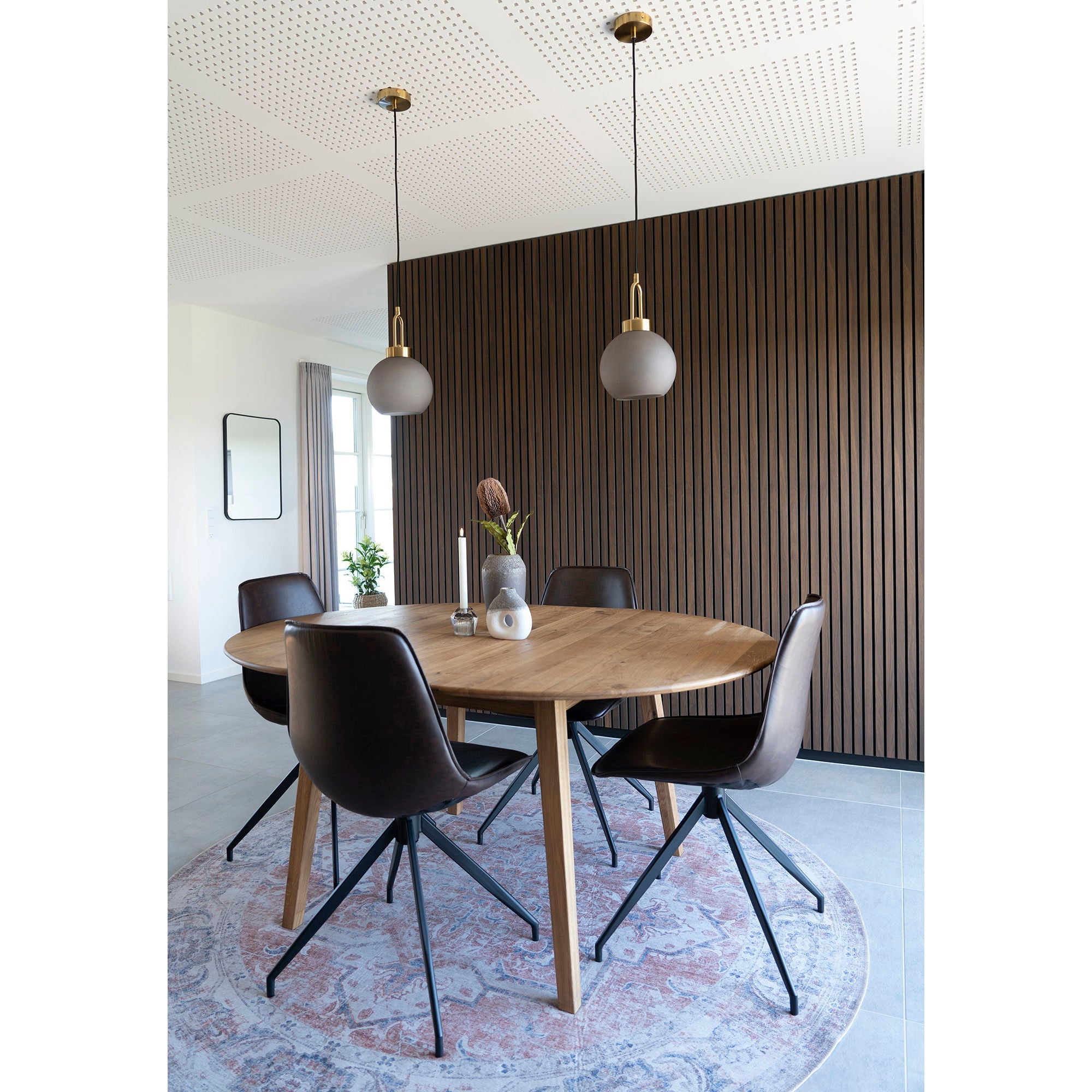 Table ronde en bois avec pieds métal noir et chaises assorties, tapis persan orange et bleu Ø200 cm