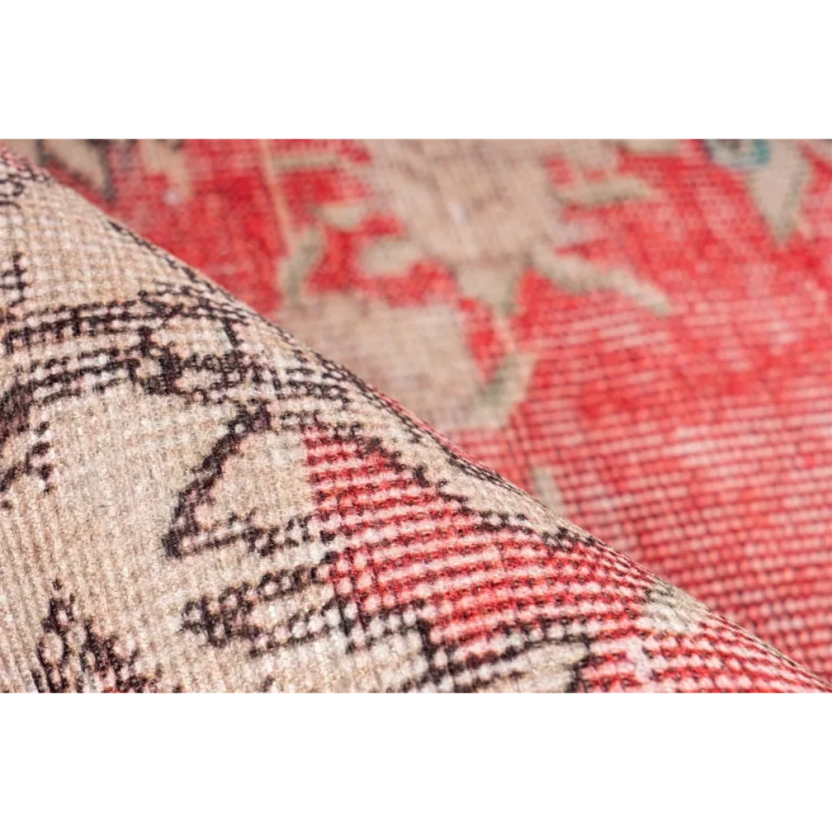 Tapis vintage rouge et beige à motifs, partiellement roulé pour révéler le dessous