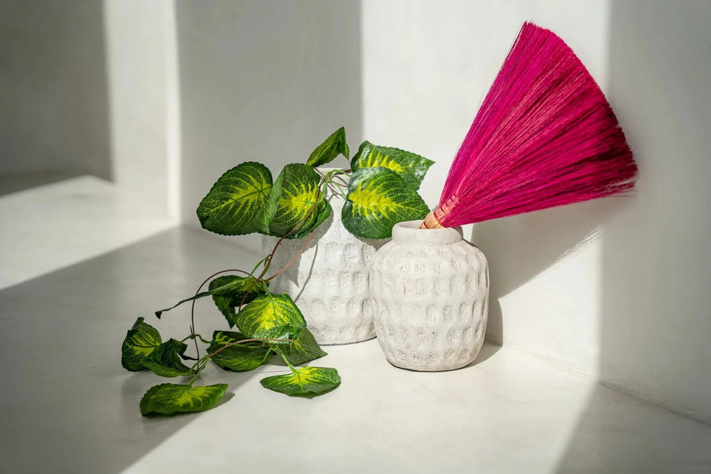 Vase cylindrique en terre cuite gris béton avec motifs en relief, décor végétal et fibre fuchsia