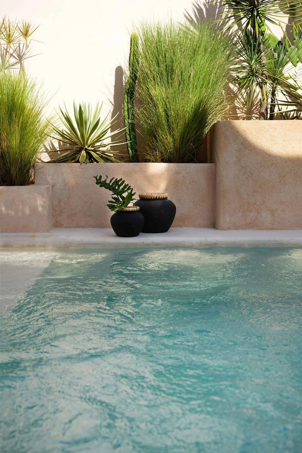 Vase décoratif noir en terre cuite Ø33 cm avec reflet d’une piscine calme et bleue pâle